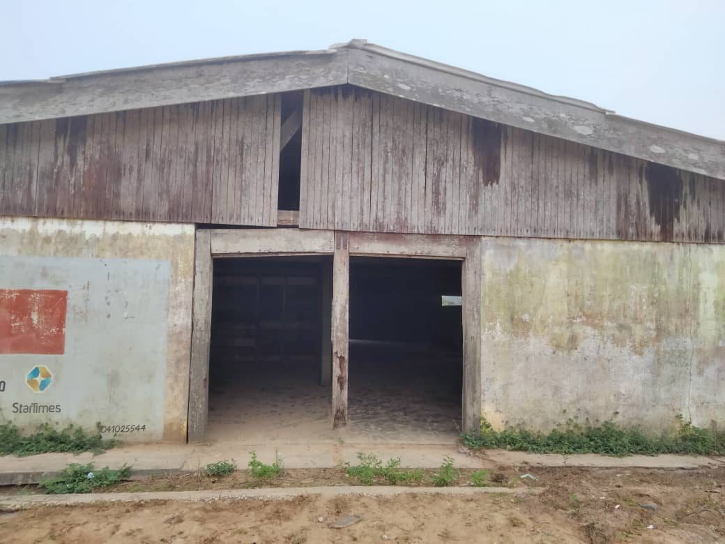 Façade du bâtiment accordé à Makola : murs défraîchis, bardage en bois, deux ouvertures sans portes